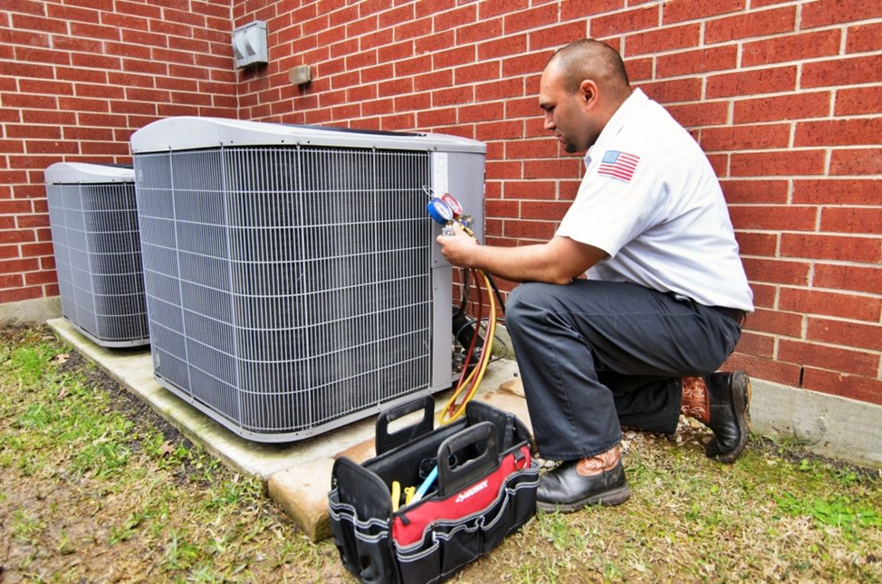 HVAC technician tuning up an outdoor AC unit during a maintenance service